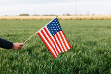 crop-faceless-person-showing-american-flag-on-field-in