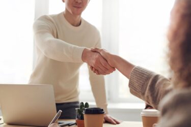 Man and woman near table shaking hands scaled