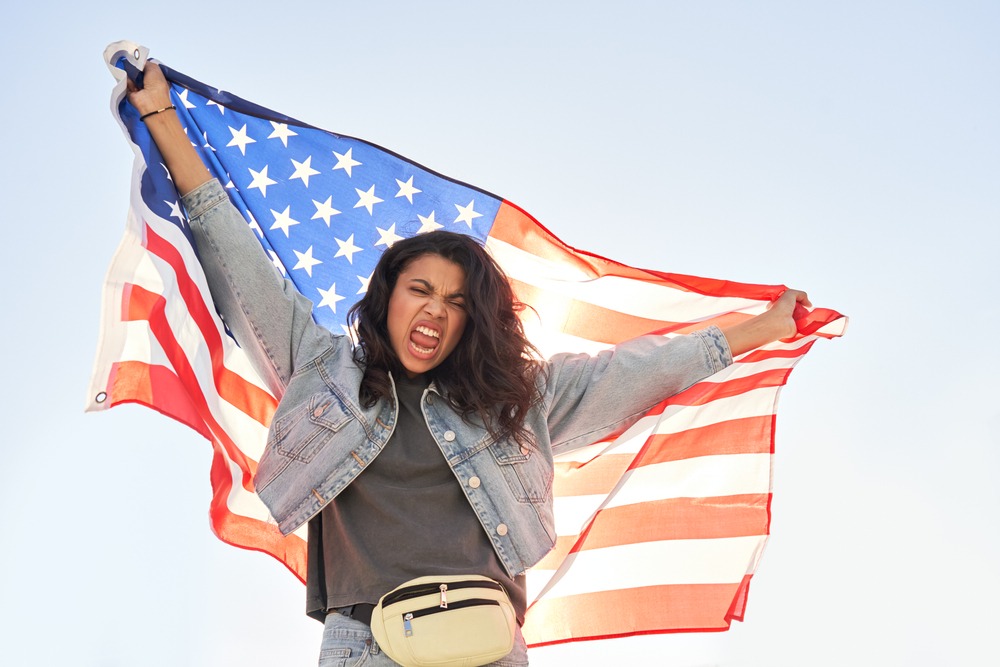 Young black woman holding USA flag. How long does it take to become a U.S. citizen?