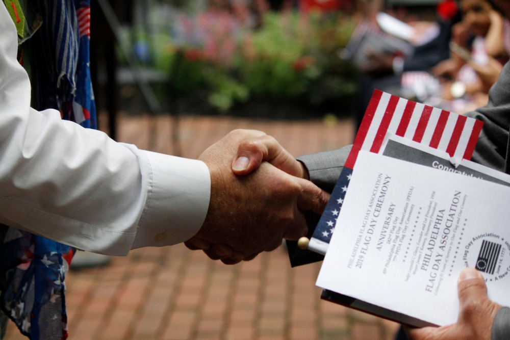 Young woman holding passport and American flag. What to expect at your naturalization interview?