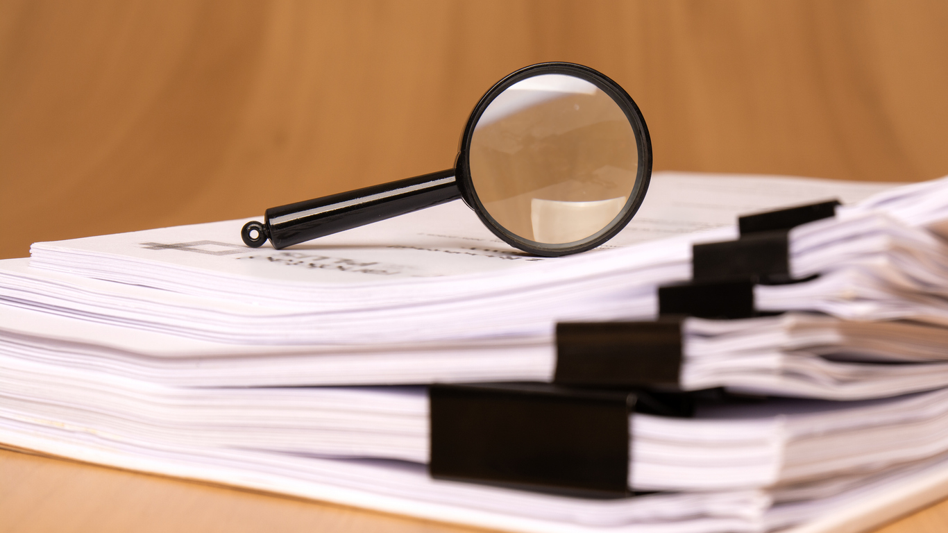 magnifying glass on stacks of papers