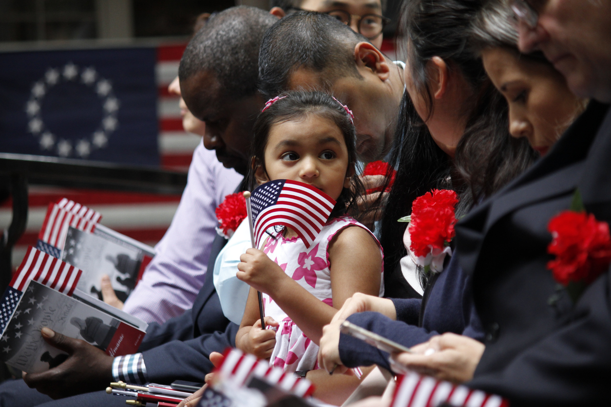 Immigrants sitting together, holding American flags