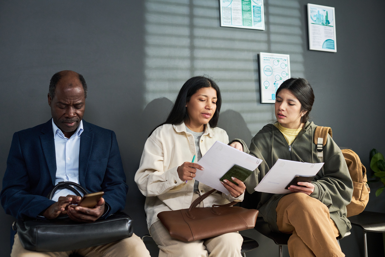 Three people sitting in chairs and looking at a document