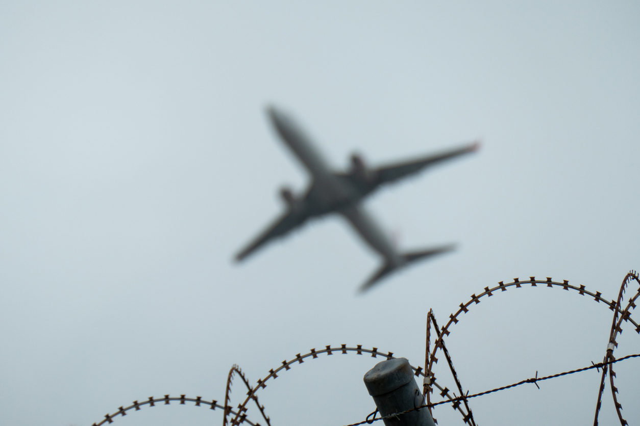 Airplane flying over a barbed wire fence