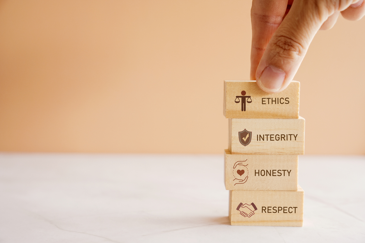 Fingers stacking small blocks that say ethics, integrity, honesty, respect.