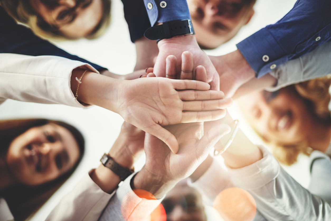 Several people in a circle putting their hands together in the middle